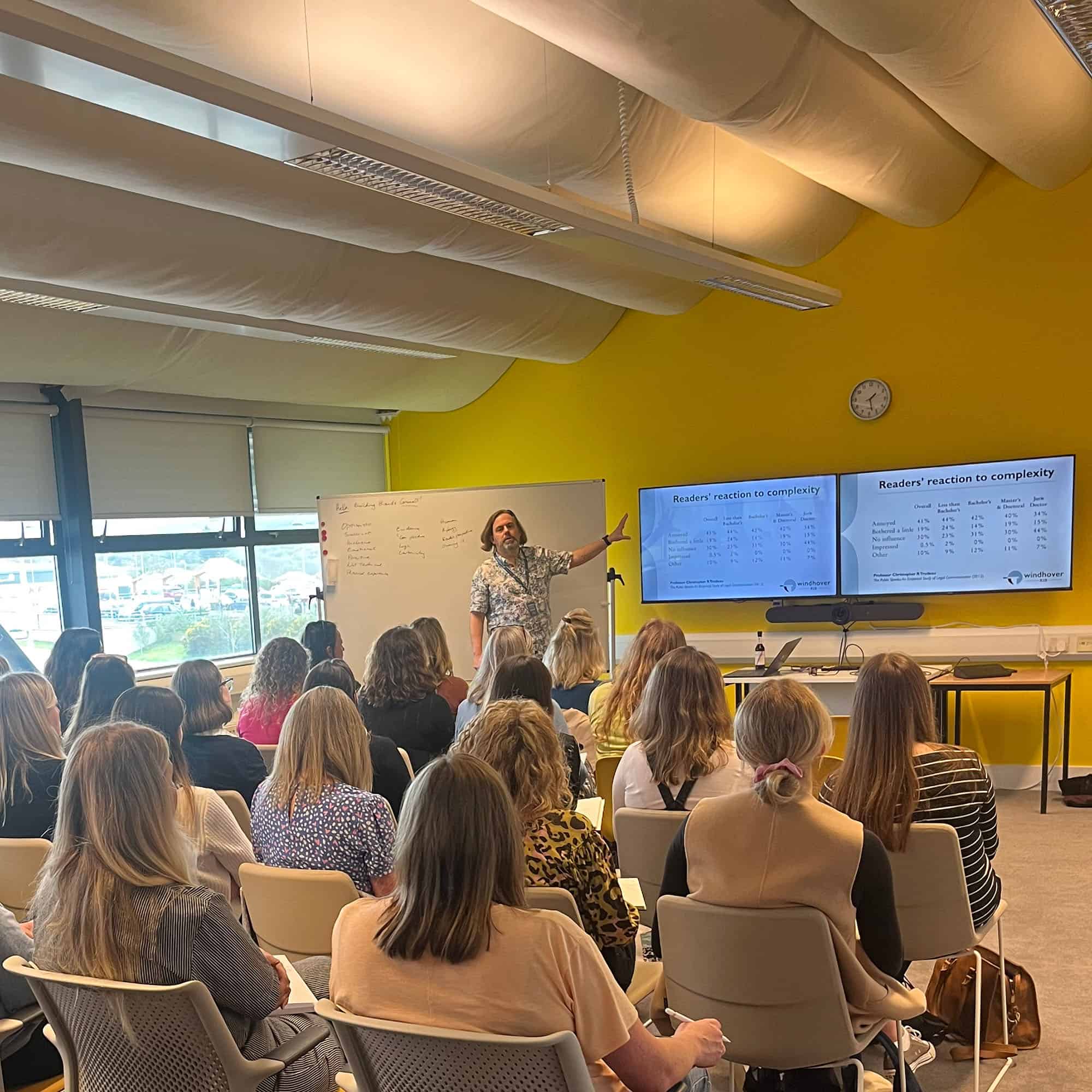 David McGuire, delivering training at Building Brands Cornwall. He’s standing in front of a room full of people, next to a screen showing readers’ reaction to complexity. The research is from Professor Chris Trudeau’s “The Public Speaks” (2012).