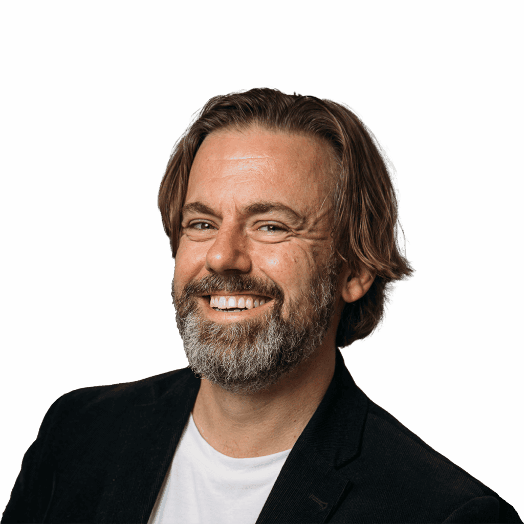 Head-and-shoulders shot of David McGuire. He’s a white, middle-aged man with a beard and floppy hair, wearing a tee shirt under a corduroy blazer. He’s clearly trying to look creative, but still very B2B.