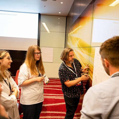 David McGuire in the lanyard and parrot shirt again, peering intently at some more chart paper scribbles on a wall.